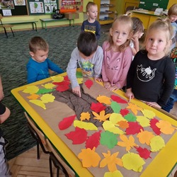 Dzieci prezentują pracę plastyczną przedstawiającą kolorowe drzewo.jpg