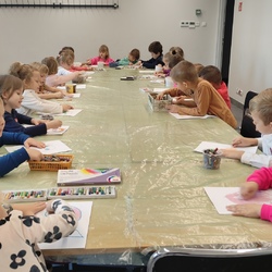 przedszkolaki siedzą przy stole i malują portret pastelami.jpg
