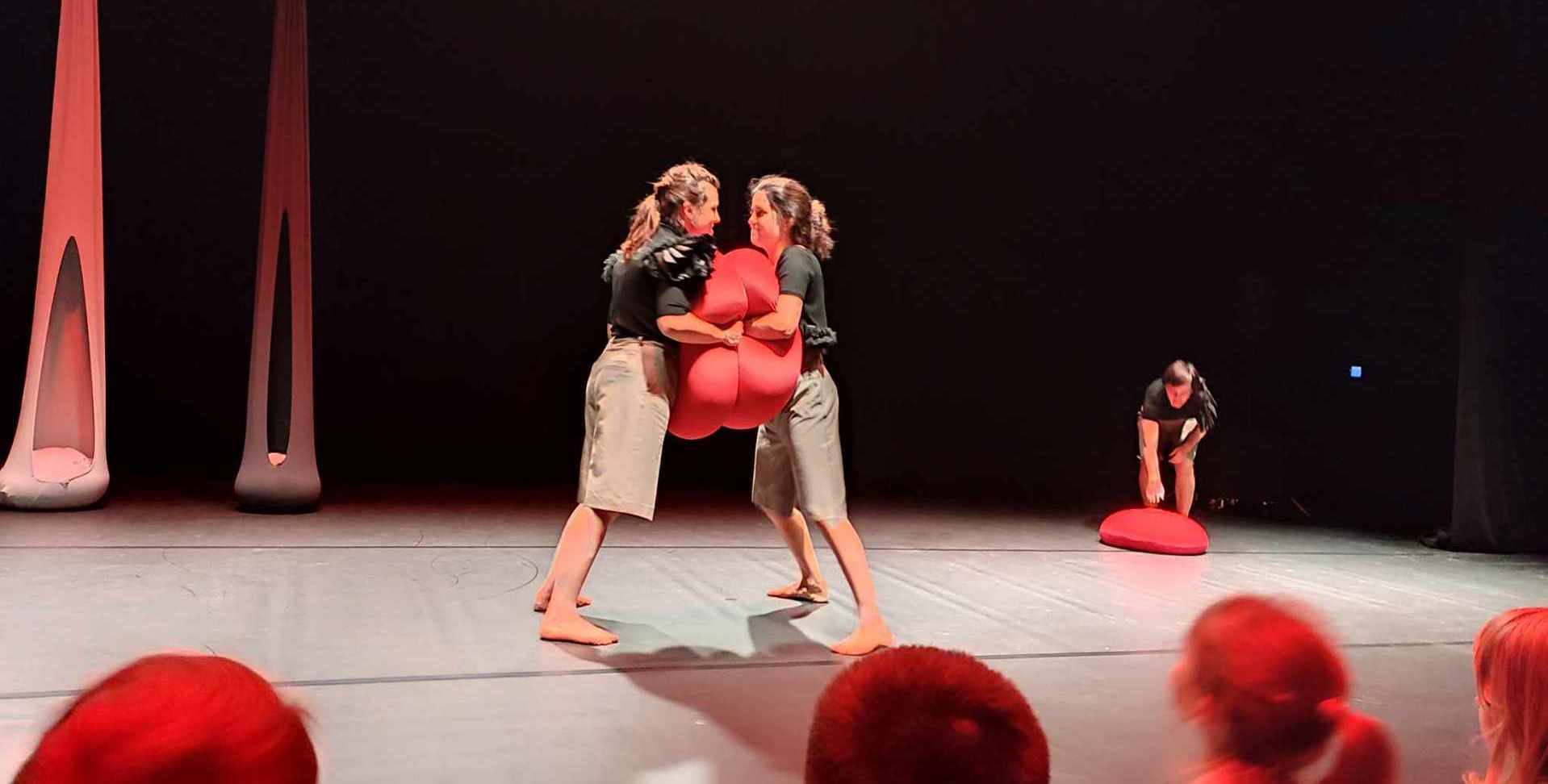 aktorki stoją na scenie i trzymają między sobą czerwoną poduszkę.jpeg