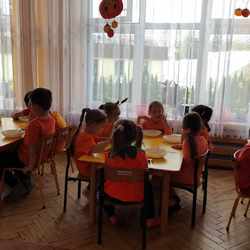 dzieci siedzą przy stolikach i spożywają obiad.jpeg