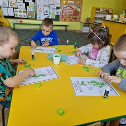 Dzieci przy stolikach przyklejają kawałeczki  papieru.jpg