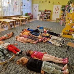 Dzieci leżą na podłodze z zamkniętymi oczami.jpg