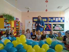 dzieci trzymają na materiale żółte i niebieskie balony.jpg