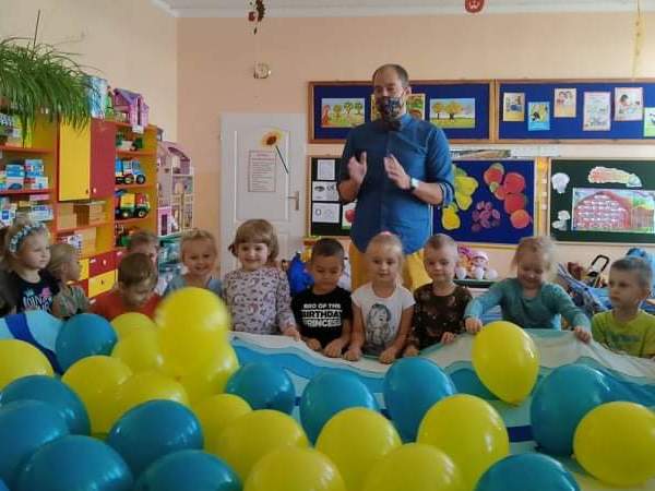 dzieci trzymają na materiale żółte i niebieskie balony.jpg