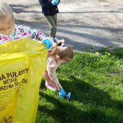 dziewczynka podnosi śmieci z trawnika.jpg