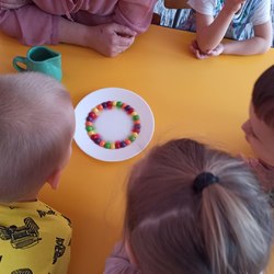 dzieci patrzą na kolorowe cukierki na talerzeu.jpg