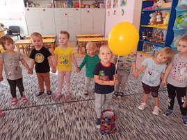 chłopiec z żółtym balonikiem stoi w kole pośród dzieci.jpg