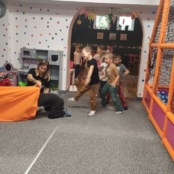 Dzieci uczestniczą w zabawie przechodzenia przez materiałowy tunel.jpg